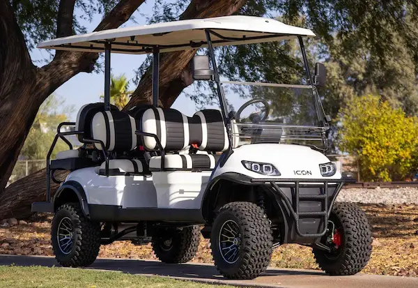 White ICON i60L lifted golf cart with 6-passenger seating, off-road tires, and black-and-white upholstery in Florida landscape